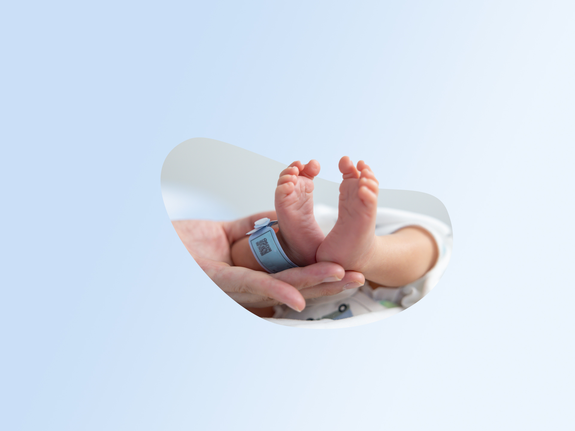 Due mani adulte sorreggono i piedini di un neonato con un braccialetto identificativo.